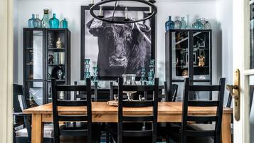 Un coin repas avec une table en bois et des chaises noires, entouré de meubles noirs aux portes vitrées, dans lesquels sont exposés divers objets.