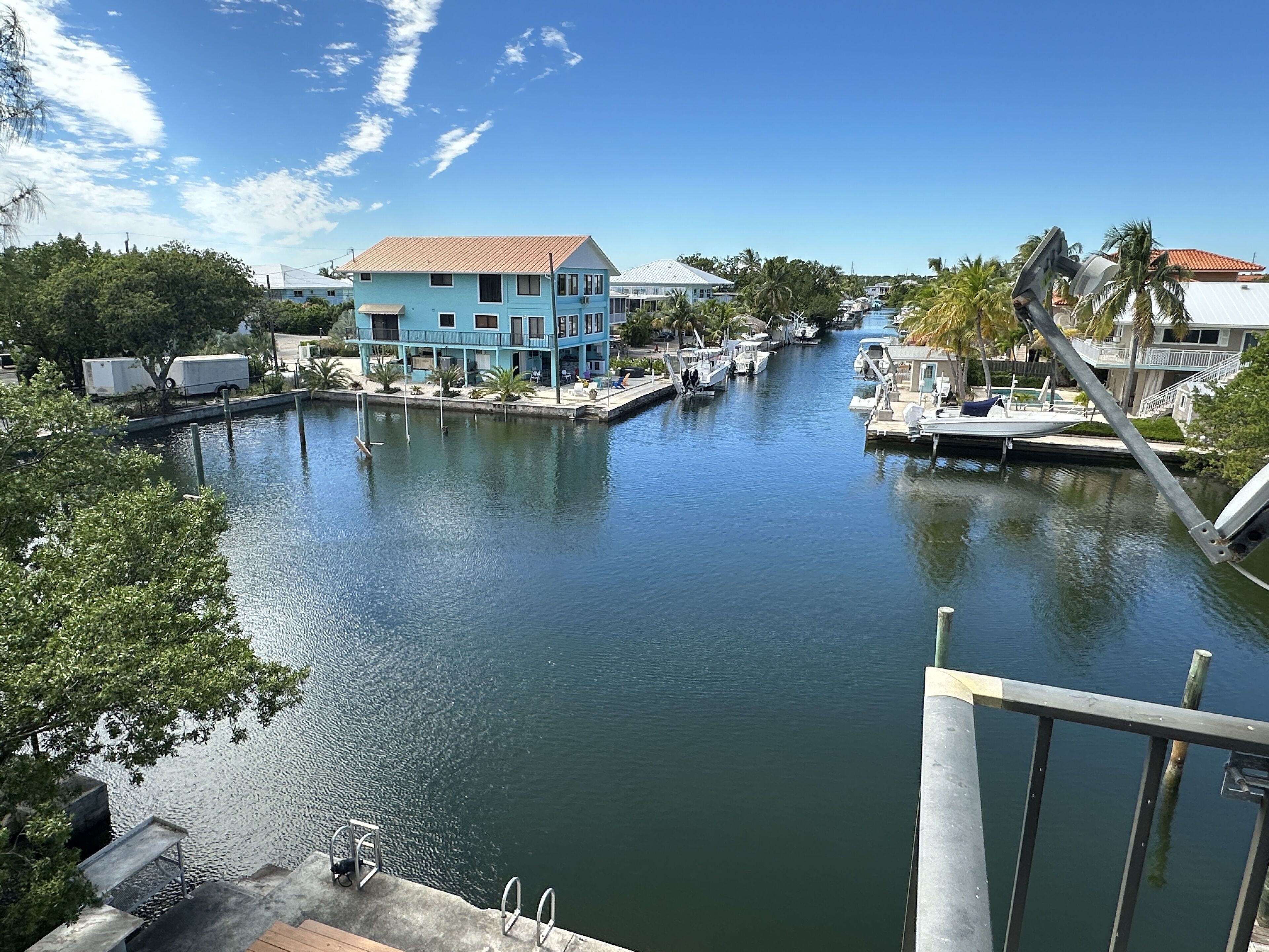 A marina with boats docked, a blue building, and a clear sky.