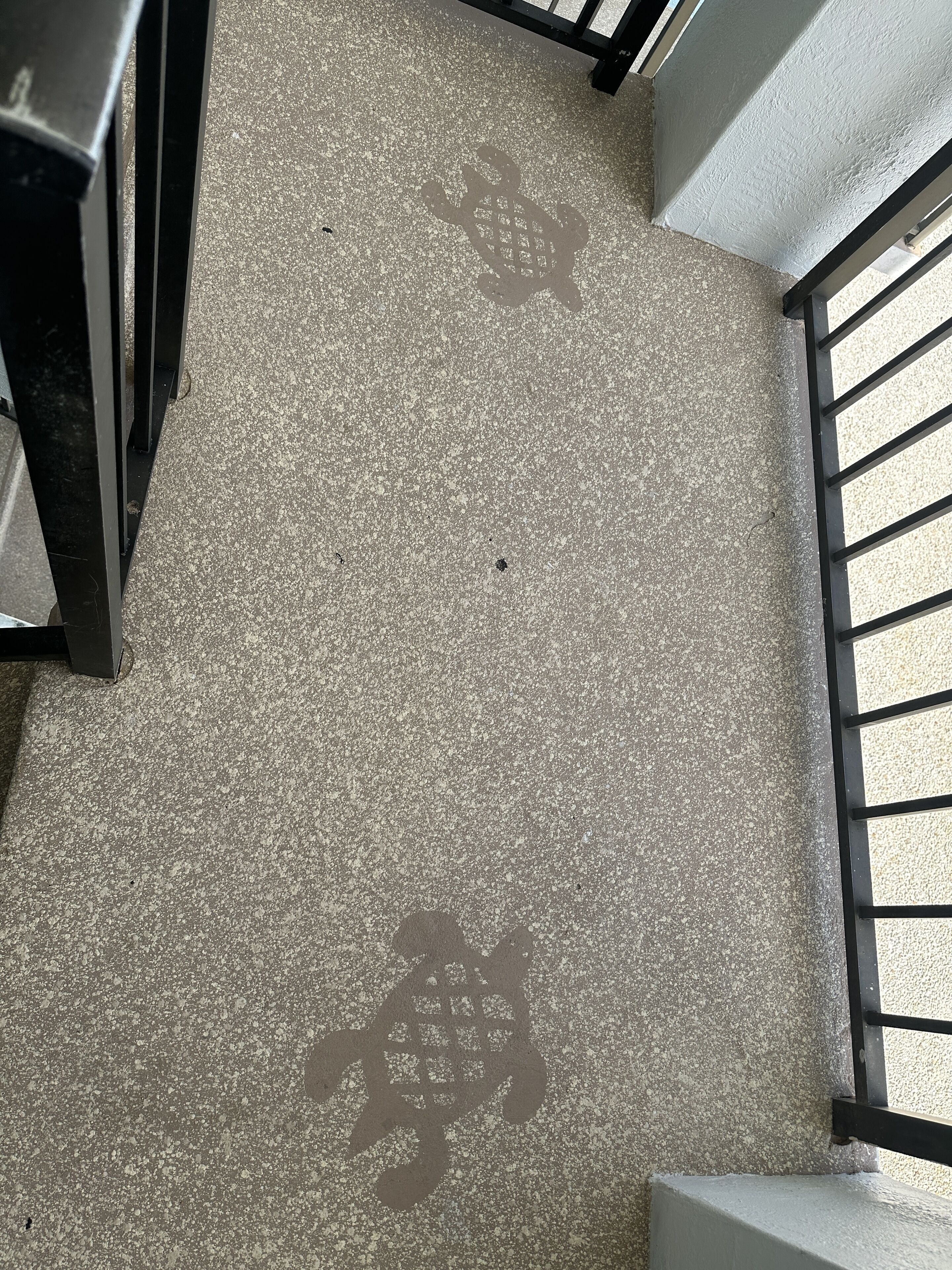 A staircase with a speckled floor and a metal railing.