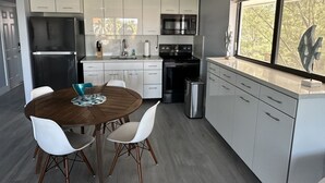 A modern kitchen with white cabinets, stainless steel appliances, and a dining area with a wooden table and white chairs. - Re-energize at our spacious condo! Get 10% off stays of 7+ days. Book now! (Key Largo)
