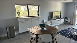 A modern dining area with a round wooden table, white chairs, and a blue bowl. - Re-energize at our spacious condo! Get 10% off stays of 7+ days. Book now! (Key Largo)