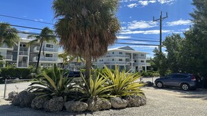 Een hotel met meerdere verdiepingen, balkons, een palmboom en een snelheidsbeperking van 40 kilometer per uur.
