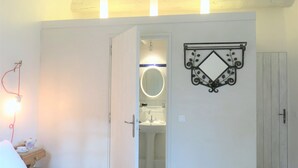 Ett sovrum med en säng, ett sängbord med en lampa, en garderob och ett badrum som syns genom en öppen dörr.