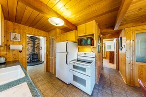 Compact kitchen with refrigerator, microwave, double oven, sink, and window.