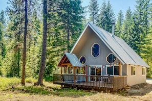 Surrounded by a dense forest, this lodge features a spacious outdoor area with a large deck and octagonal skylight.