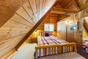 Cozy attic bedroom with a sloped ceiling, featuring a single bed and a wooden headboard.
