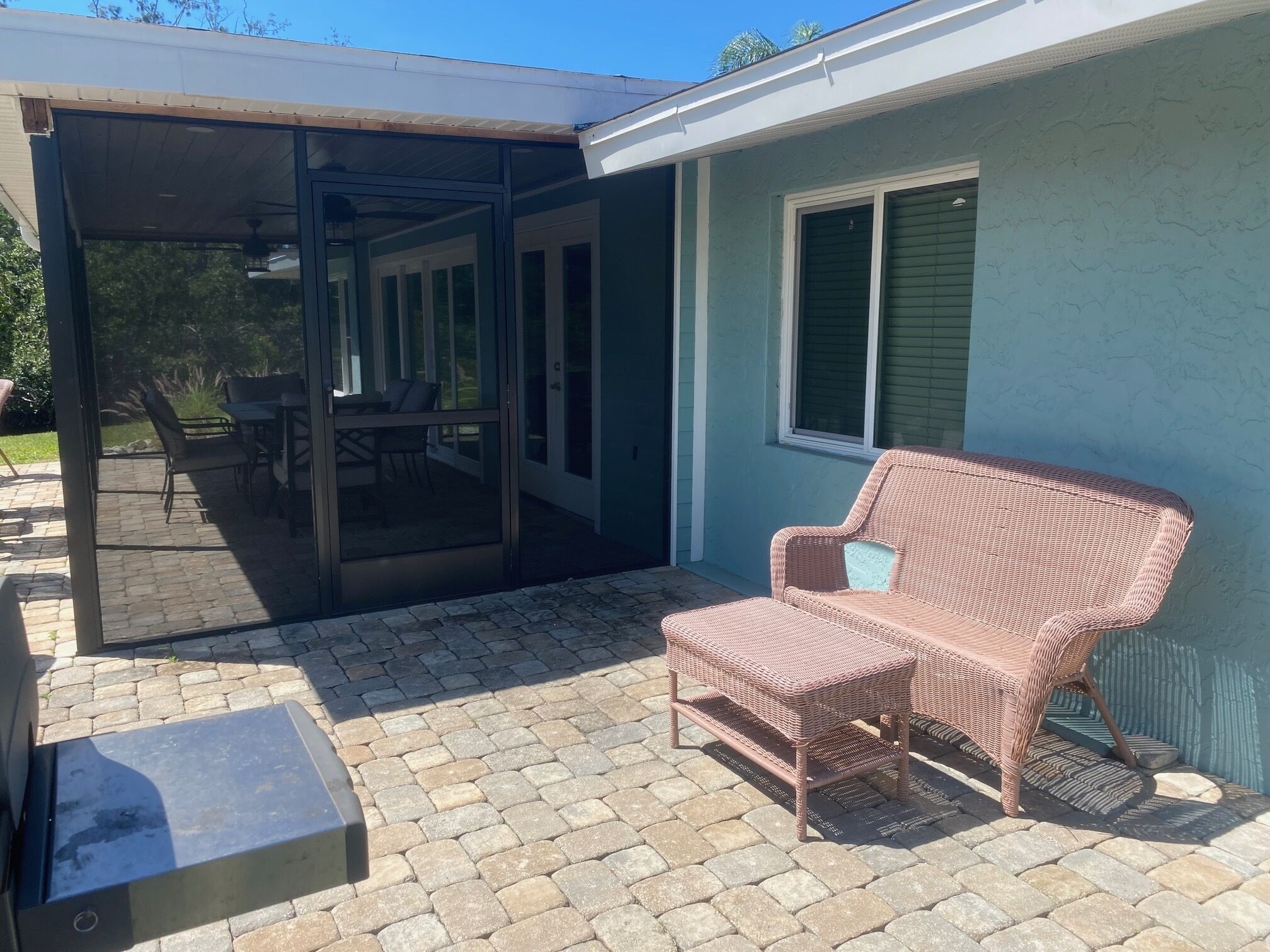 A covered patio area with a wicker chair, a table, and chairs.