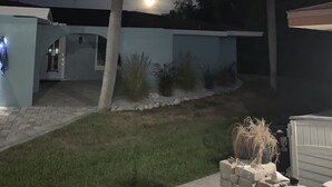 A residential house with a paved driveway, a palm tree, and a well-lit entrance.