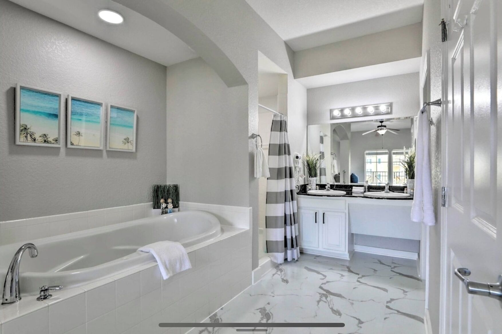 A modern bathroom with a large bathtub, a vanity with a mirror, and a shower area.