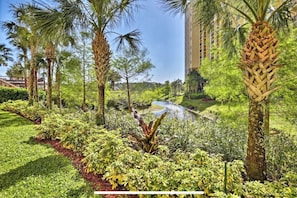 Jardín ajardinado con palmeras, una pequeña fuente de agua y un camino.