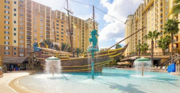 A hotel pool area with a water slide and a fountain.