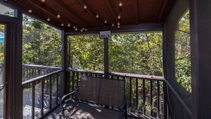 A covered deck with a wooden ceiling, string lights, and a sign indicating it's a deck area.