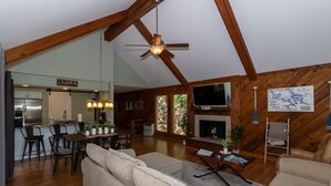 A spacious living area with a fireplace, a dining area, and a kitchen visible through an open archway.