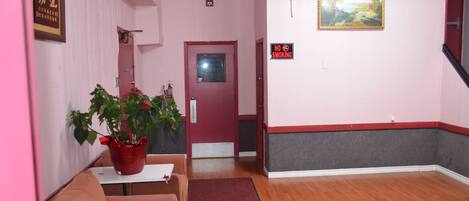 A room with a red door, a painting, a 'No Smoking' sign, a plant, and a red and white wall trim.