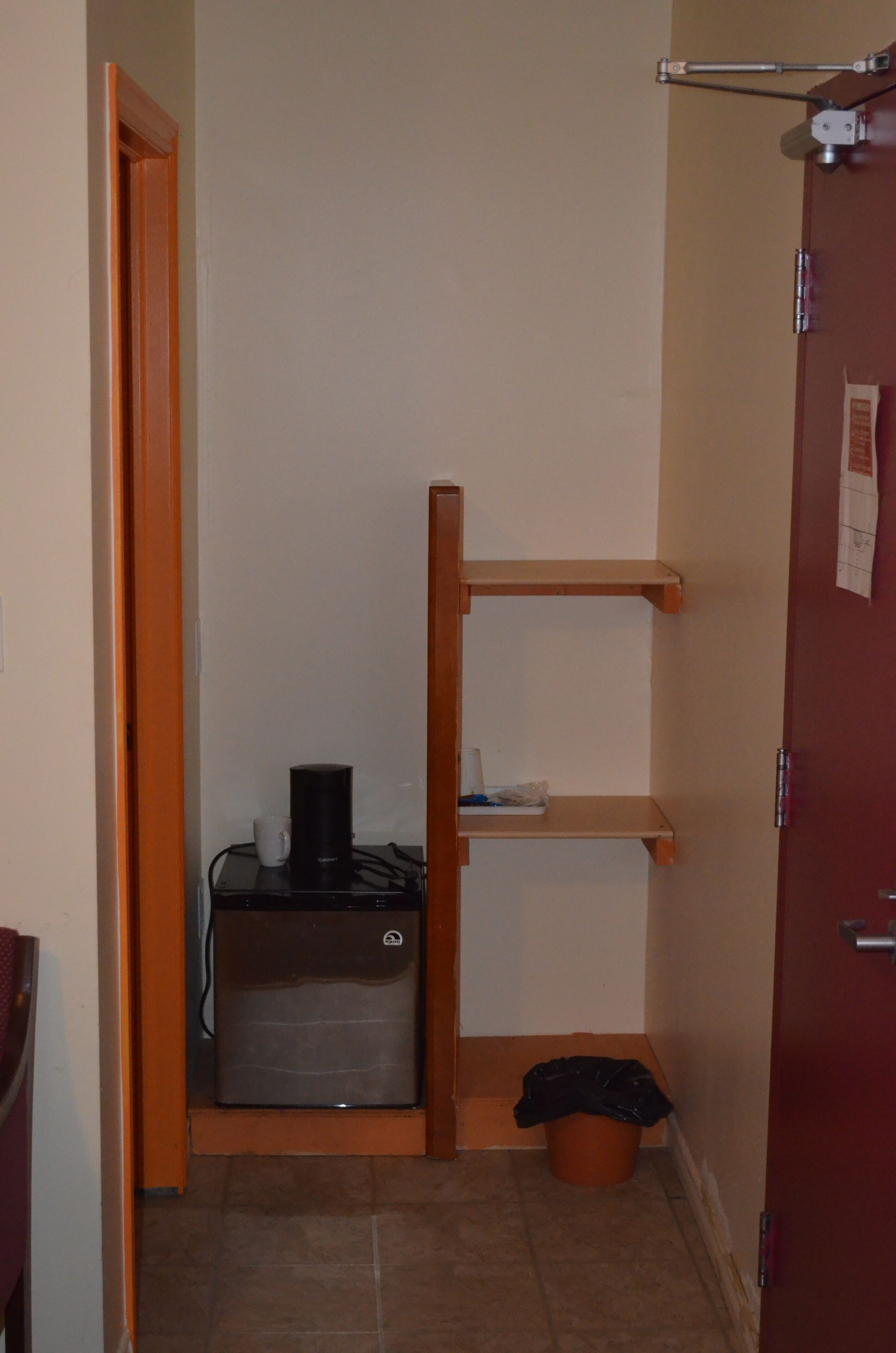 Una kitchenette compacta con refrigerador, cafetera y basurero.
