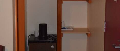 Una kitchenette compacta con refrigerador, cafetera y basurero.
