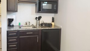 Una cocina compacta con armarios oscuros, microondas integrado y lavavajillas.