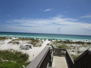 A beach with a wooden boardwalk leading to the shore, featuring beach umbrellas and people enjoying the water. - PRIVATE BEACH ACCESS!! Cozy 1st floor 1BR/1BA, Sleeps 4. Great for Families! (Miramar Beach)