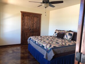 Un dormitorio con una cama grande, un ventilador de techo y un armario de madera.