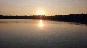 Una masa de agua tranquila reflejando el sol al atardecer.