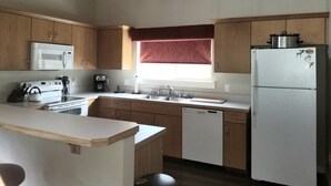 Una cucina con mobili in legno, un forno a microonde, un fornello, un lavandino e un frigorifero.