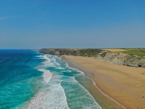 A coastal beach with clear blue waters and a sandy shore.