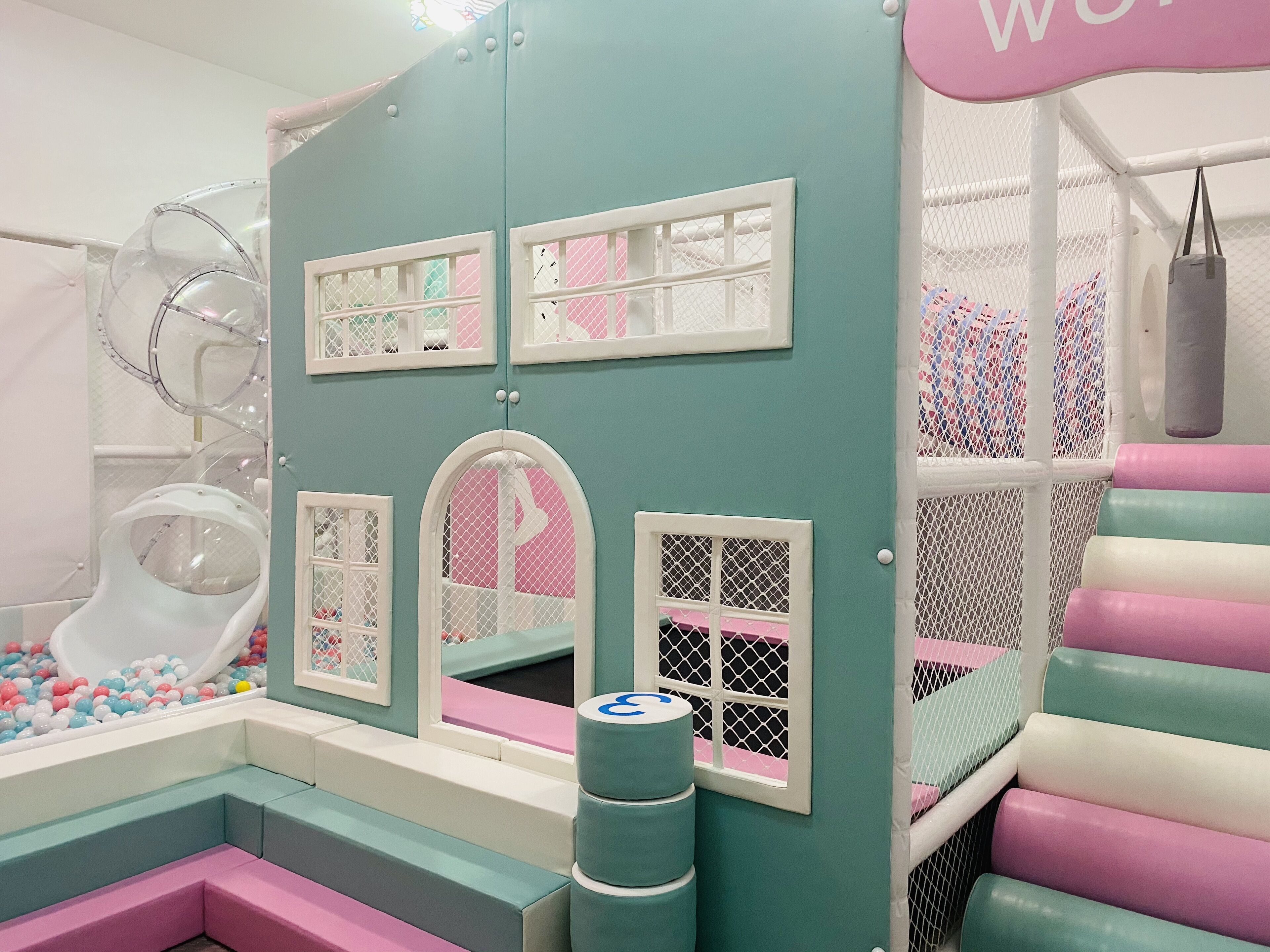 A children's play area with a slide, ball pit, and padded seating.