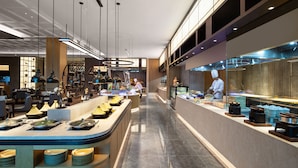Een modern restaurant met een lange toonbank, hangende verlichting en een kok die eten bereidt.