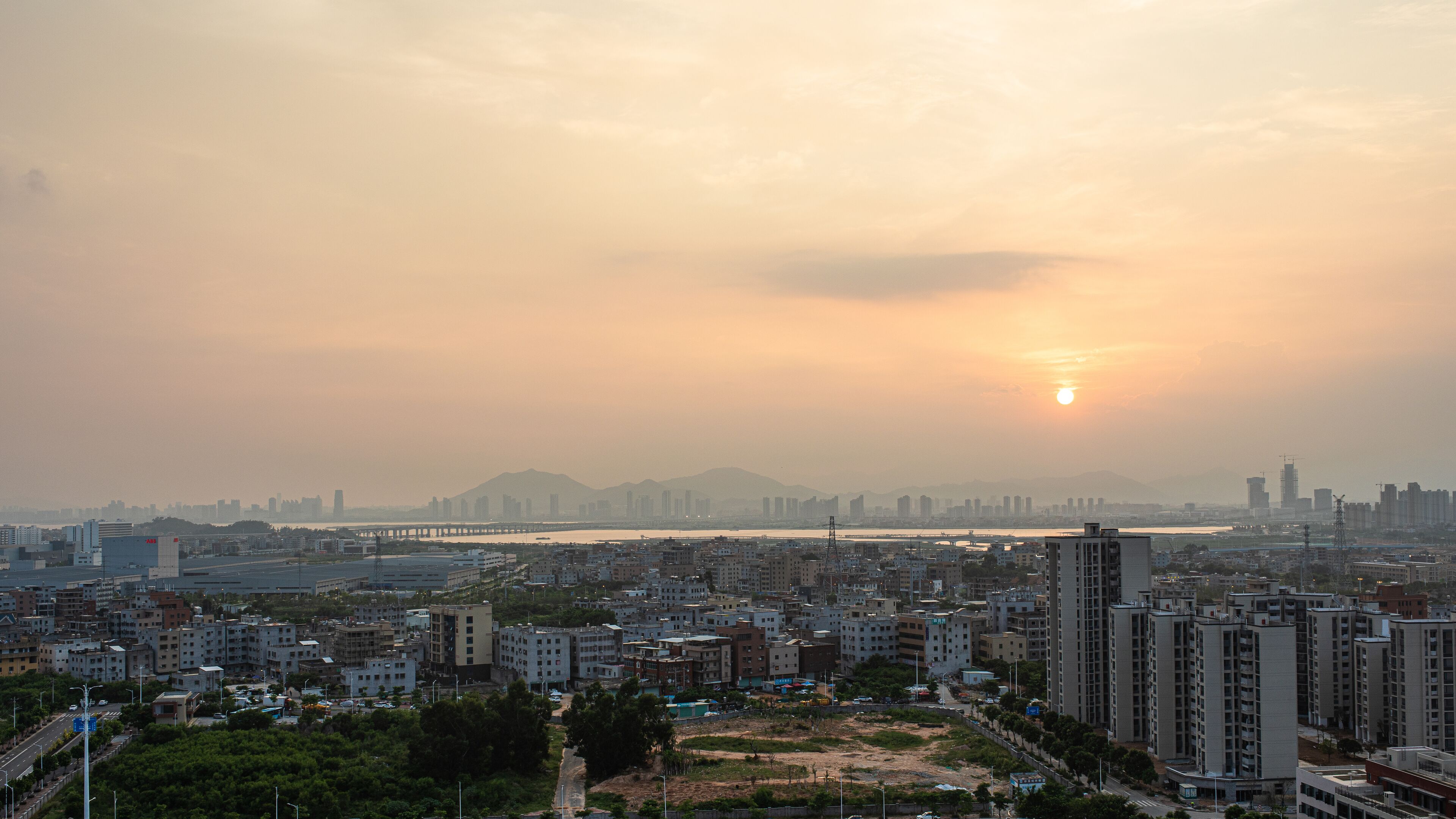Une vue urbaine avec une rivière, un pont et un coucher de soleil.