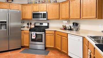 Una cocina con armarios de madera, electrodomésticos de acero inoxidable, microondas, estufa y lavavajillas.