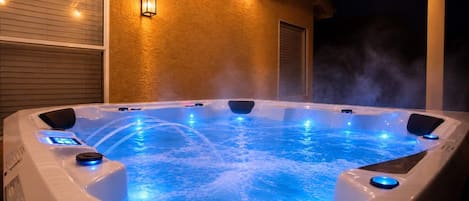 A hot tub with built-in jets and a digital control panel, surrounded by a textured wall and string lights.