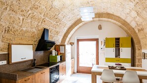 Una cocina rústica con paredes de piedra, un mostrador de madera y un comedor con mesa y sillas.