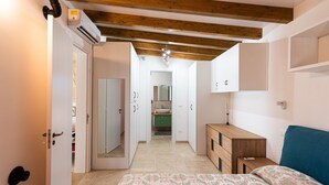 Un dormitorio con cama, cómoda de madera, mesita de noche y baño a la vista.