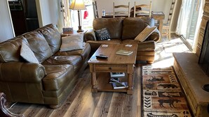 A living room with a brown leather couch, a wooden coffee table, and a patterned rug. - Misty Mountain Cabin with Grandfather Views (Blowing Rock)
