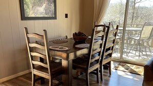 A dining area with a wooden table, chairs, and a framed picture on the wall. - Misty Mountain Cabin with Grandfather Views (Blowing Rock)