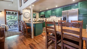 Una cucina con mobili in legno, un frigorifero in acciaio inossidabile e un'area pranzo con sedie e tavolo in legno.