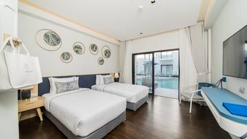 A hotel room with two beds, a desk, a TV, and a view of the pool.