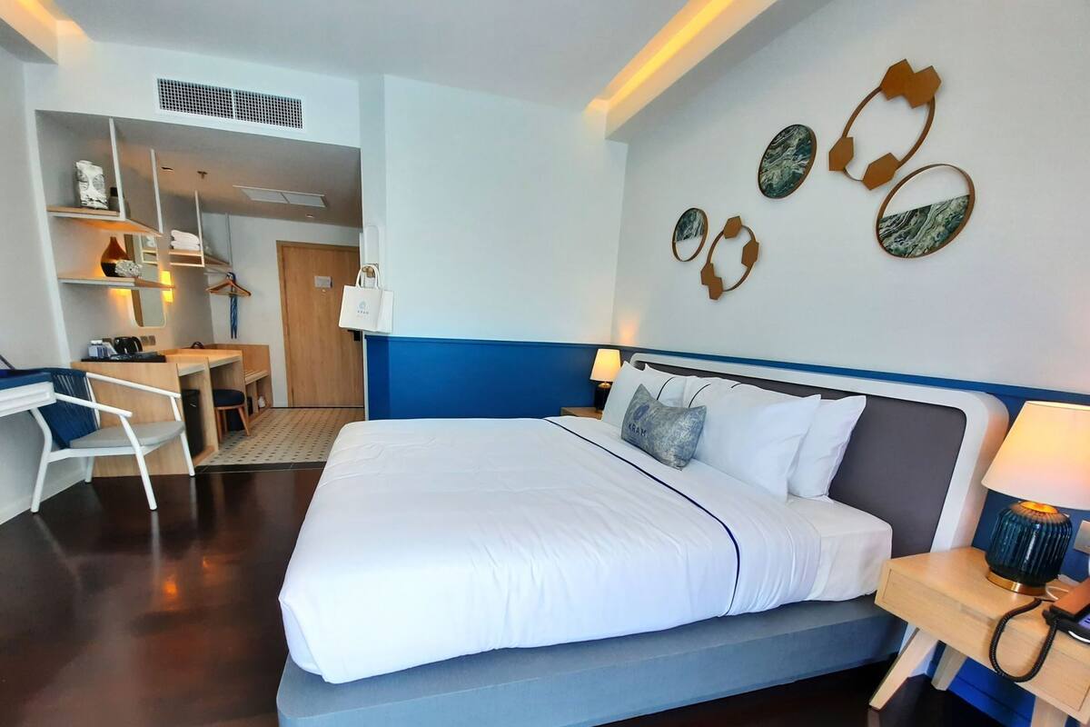 A hotel room with a large bed, a desk, and a chair, a small table, and a wall with decorative items.