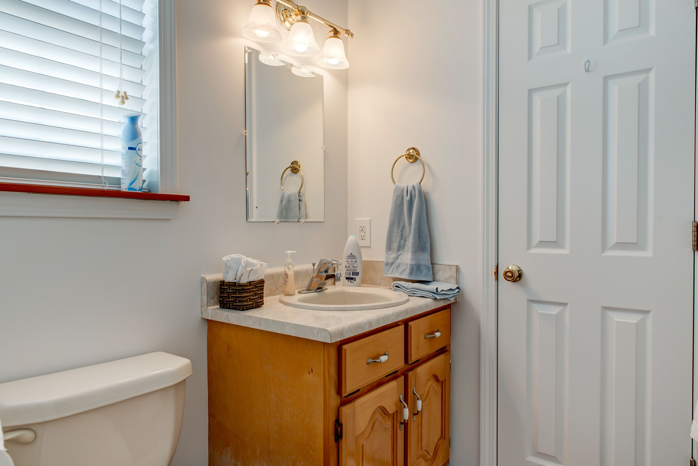 A bathroom with a toilet, sink, vanity, and a mirror.