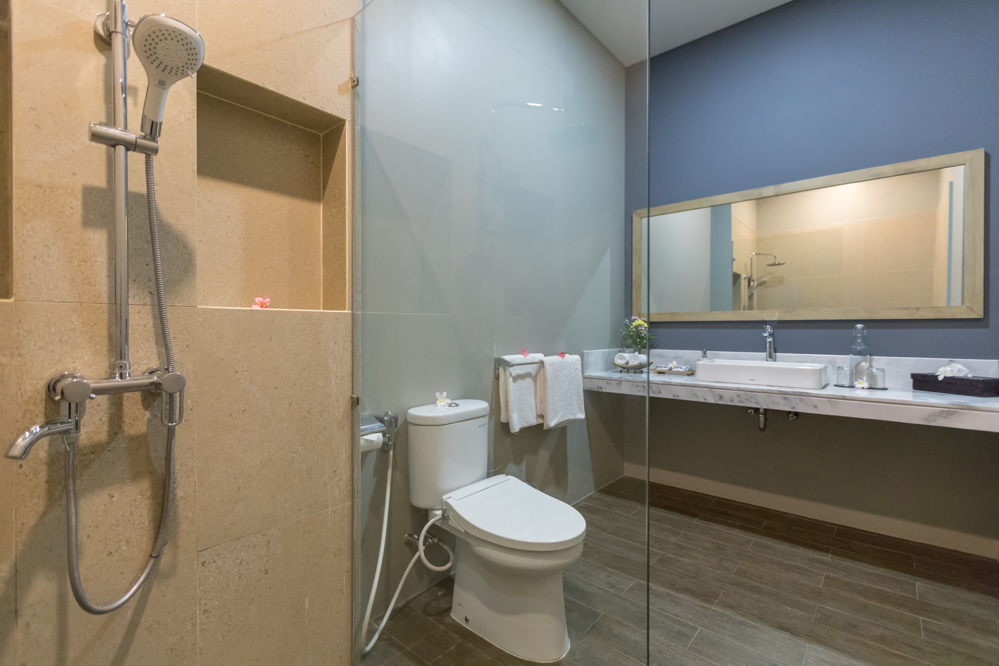 Ein modernes Badezimmer mit Duschkabine aus Glas, Toilette und Waschbecken mit Spiegel.