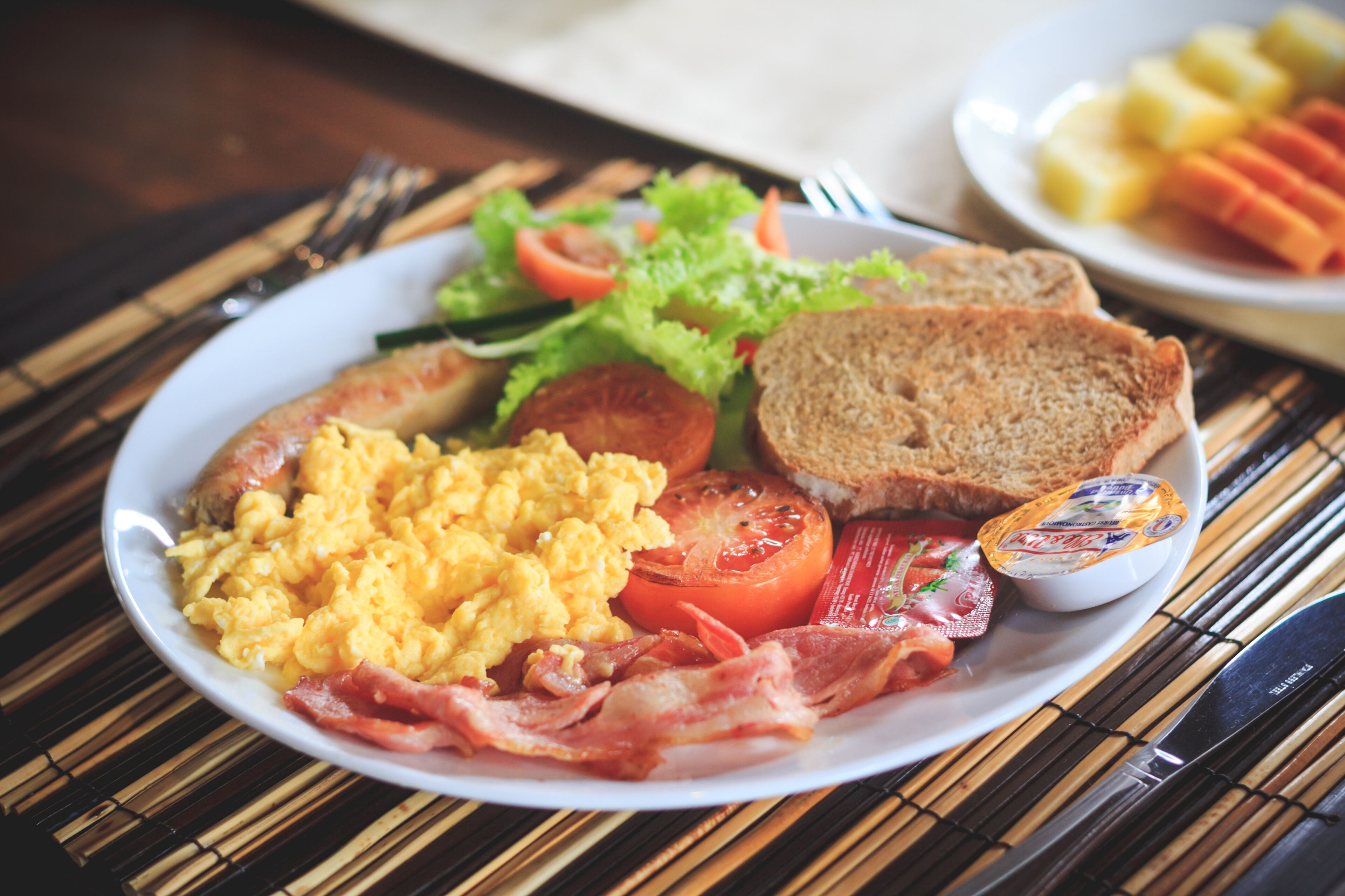 A plate of breakfast food including scrambled eggs, bacon, toast, and a side salad.