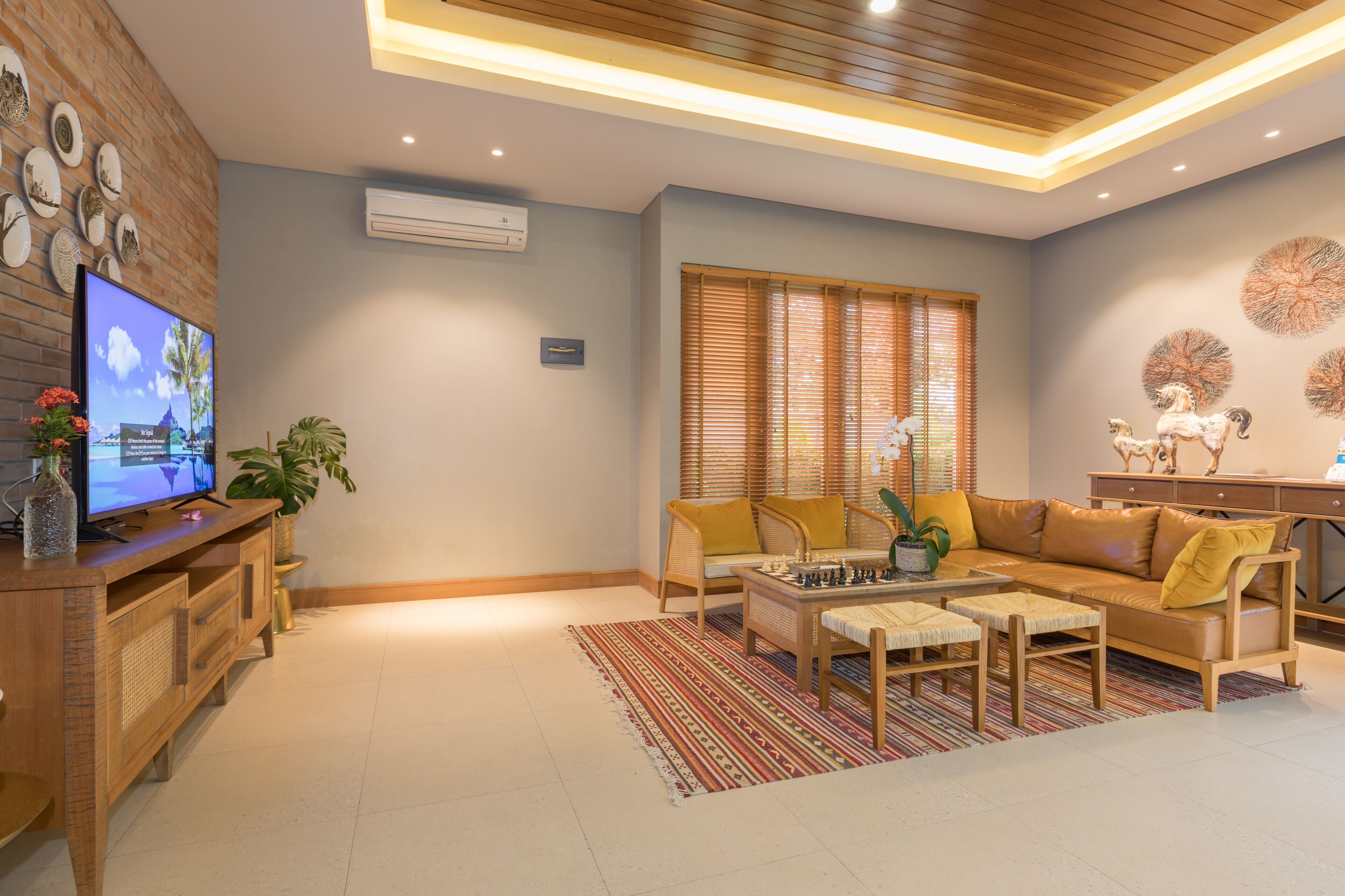 A modern living room with a wooden ceiling, a television, a sofa, a coffee table, and a patterned rug.