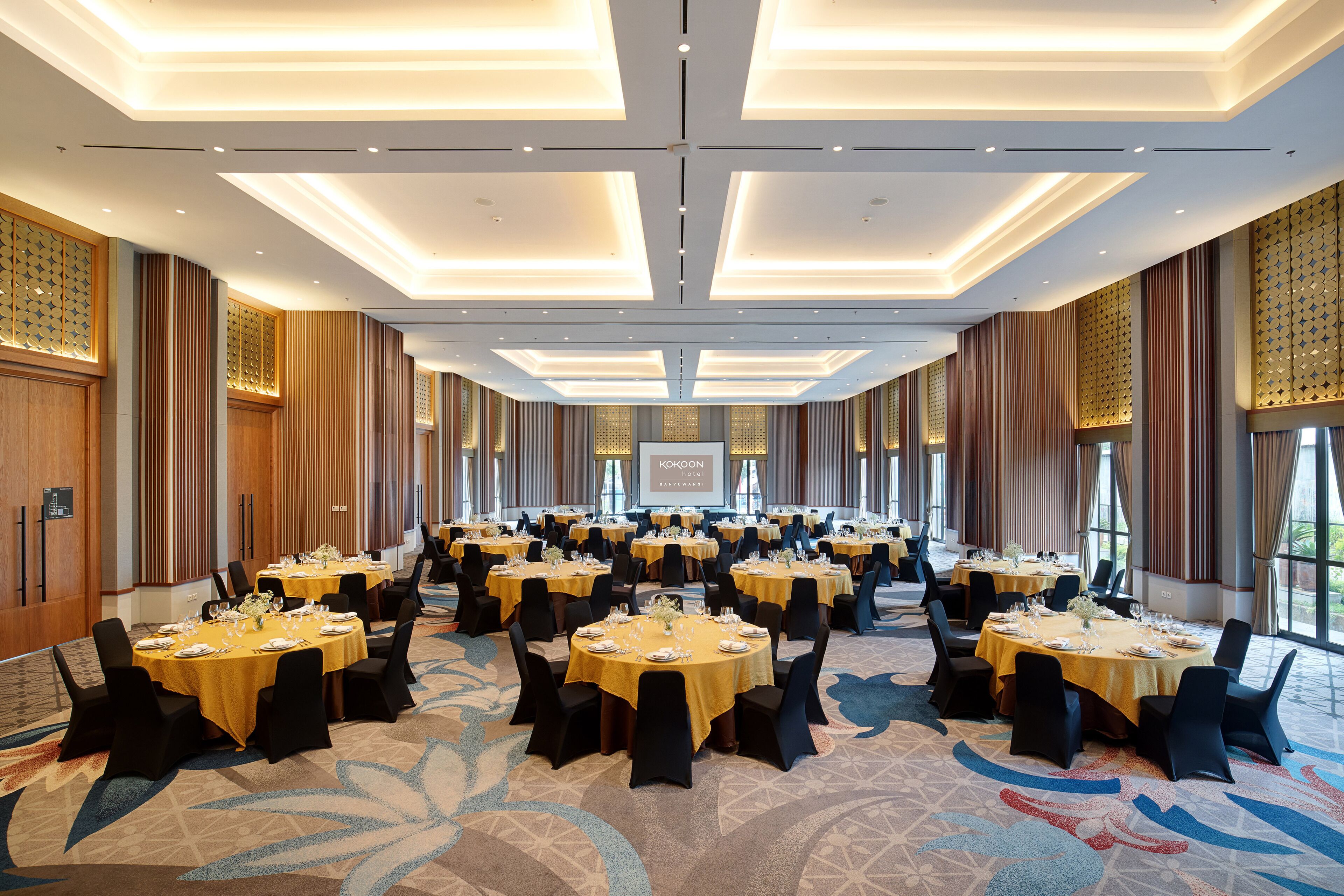 A large conference room with multiple round tables, each set with chairs and table settings.