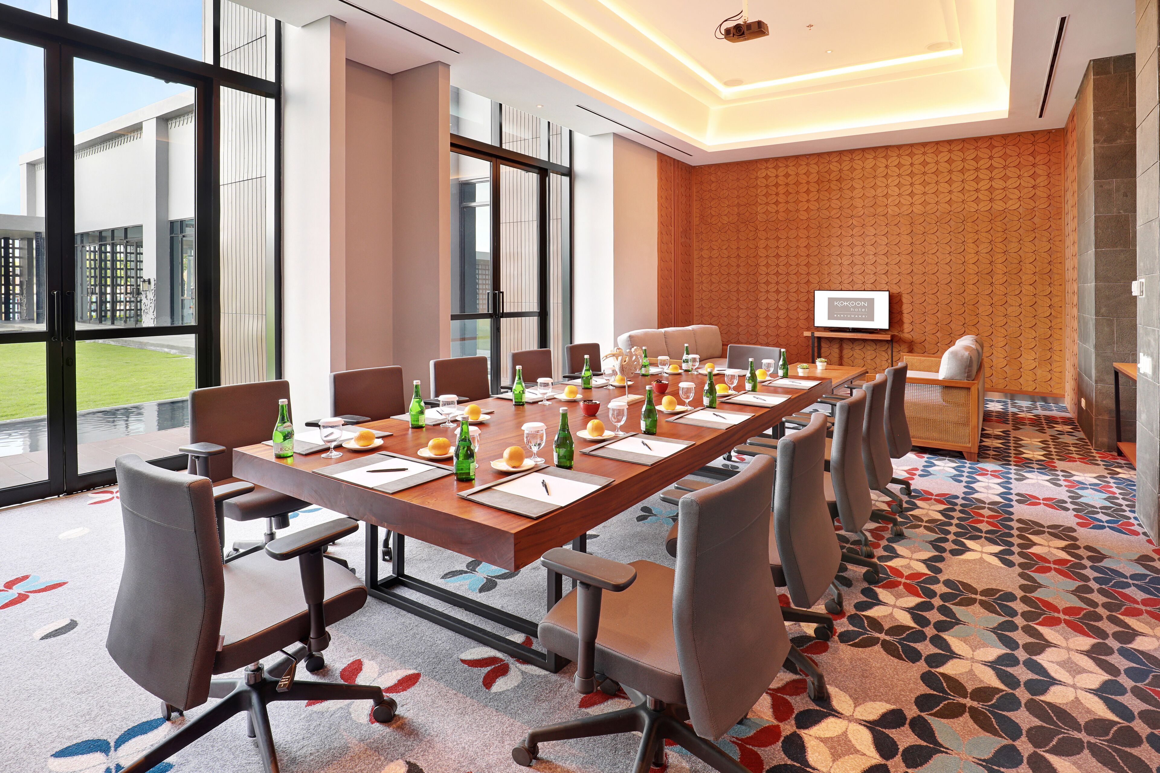 A conference room with a long table, chairs, and a TV screen.