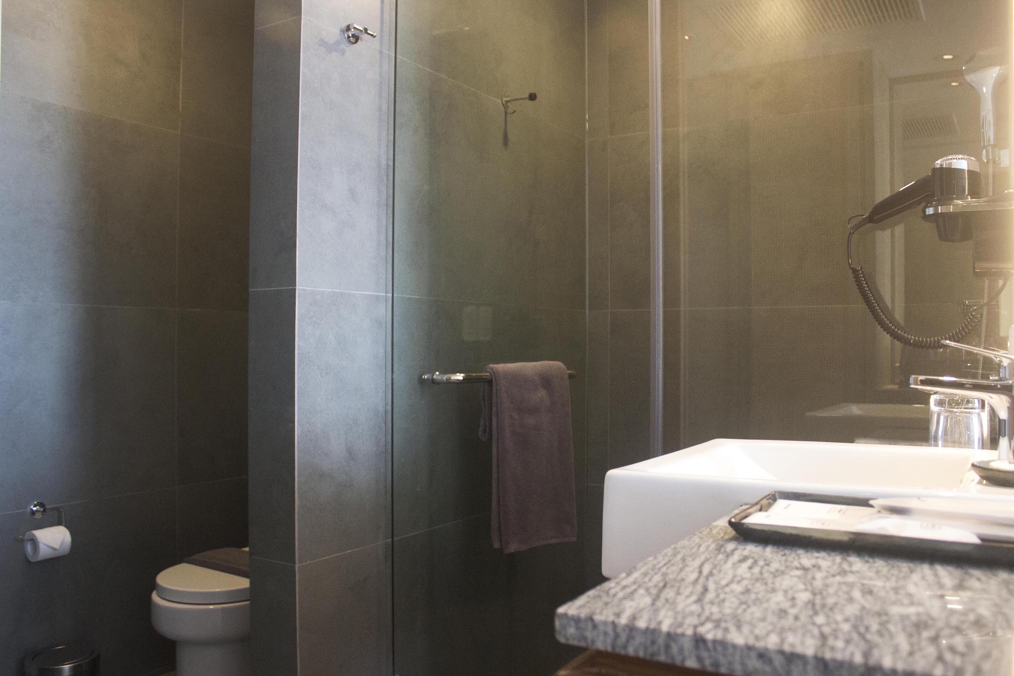 A modern bathroom with a shower, toilet, and sink.