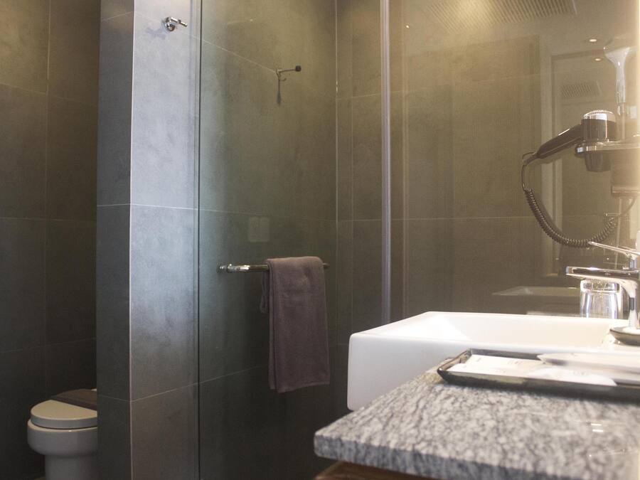 A modern bathroom with a shower, toilet, and sink.