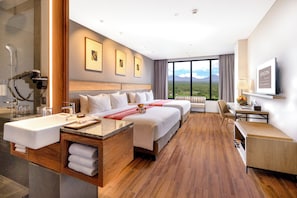 Une chambre d’hôtel avec un grand lit, un bureau, une salle de bain et une vue sur le paysage.