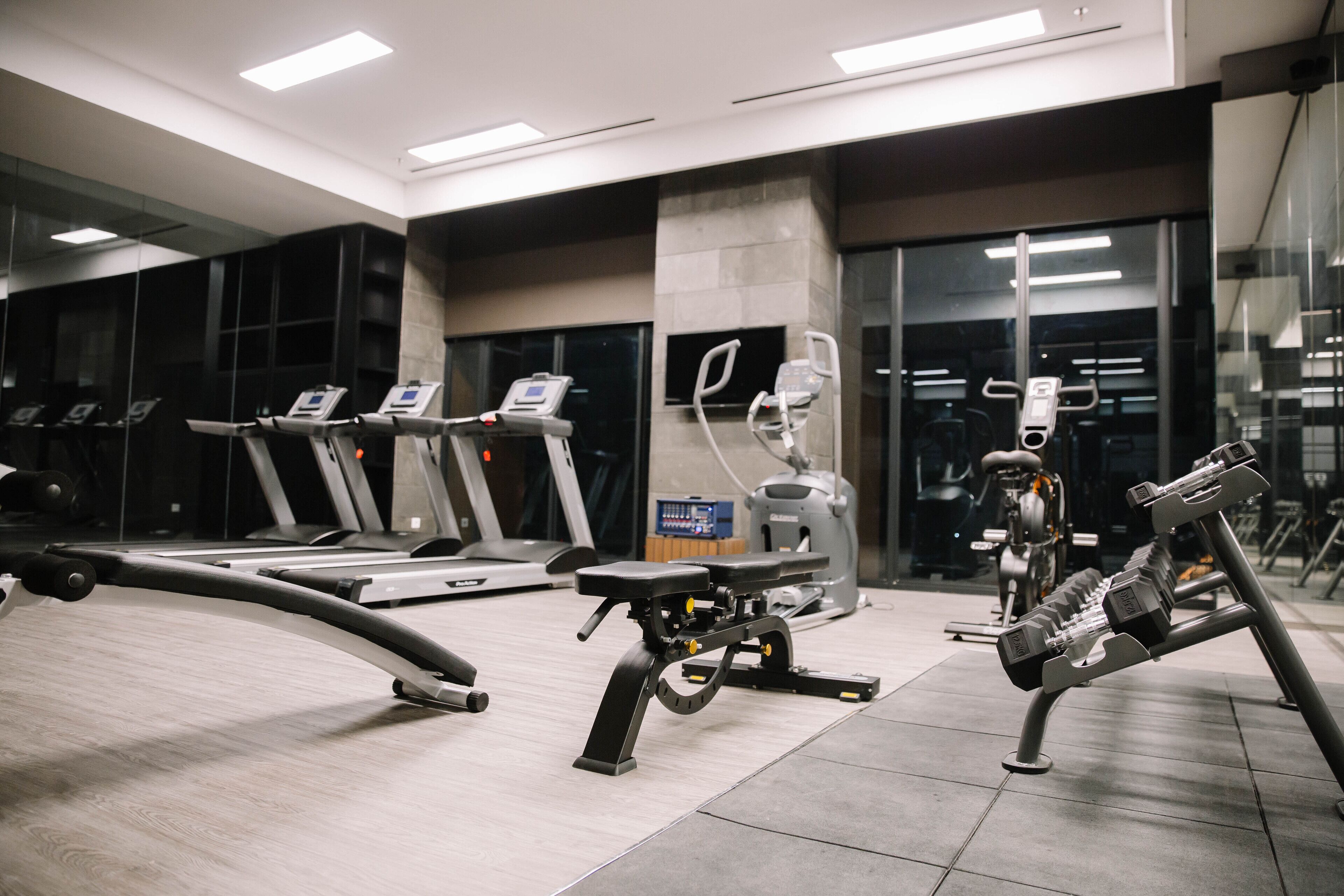Une salle de sport moderne équipée de tapis de course, d’un vélo d’appartement et de matériel de musculation.