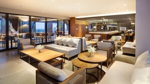 A modern lounge area with sofas, tables, and a bar.