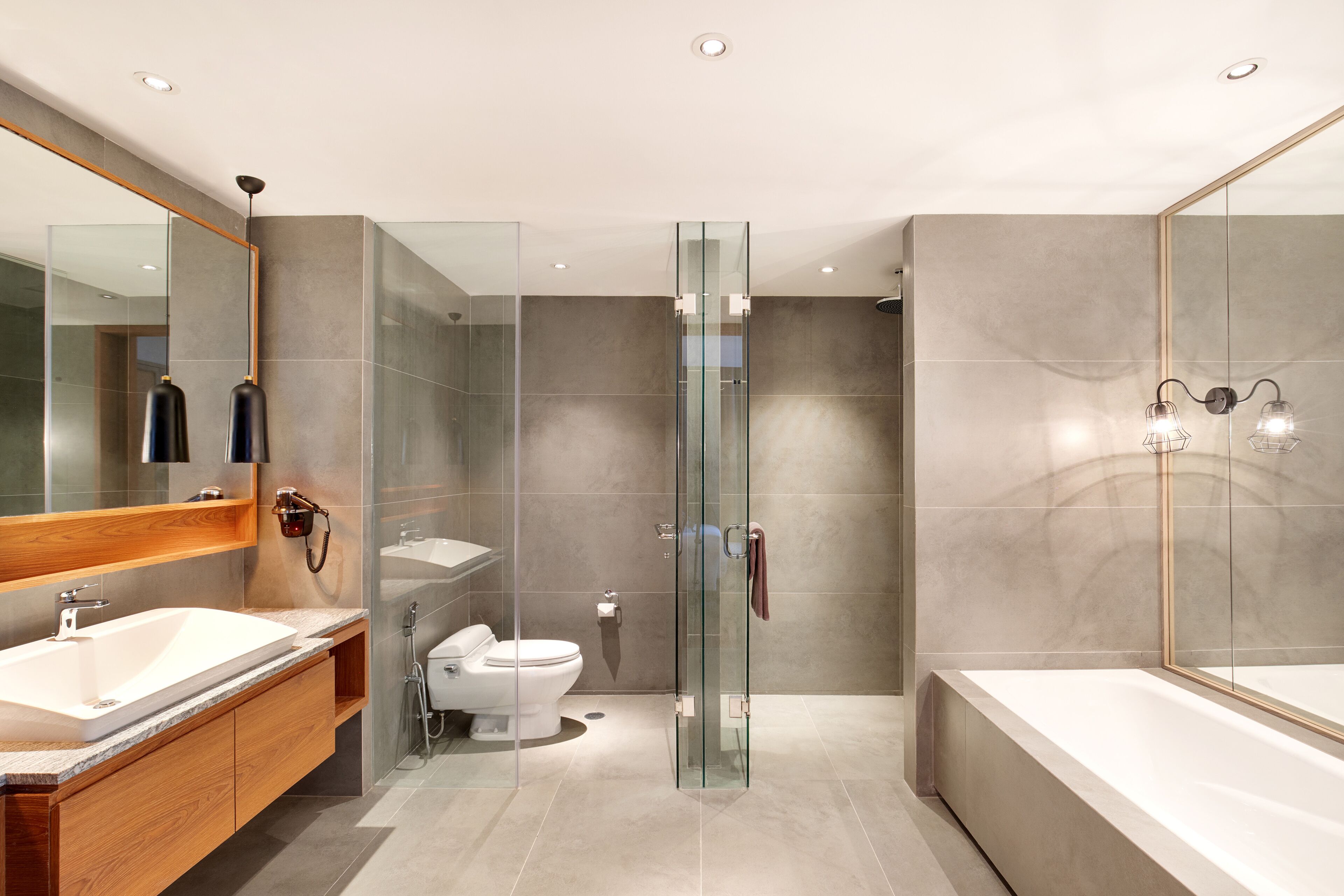 Ein modernes Badezimmer mit einer gläsernen Duschkabine, einer großzügigen Badewanne und einem Waschtisch mit Waschbecken und Spiegel.